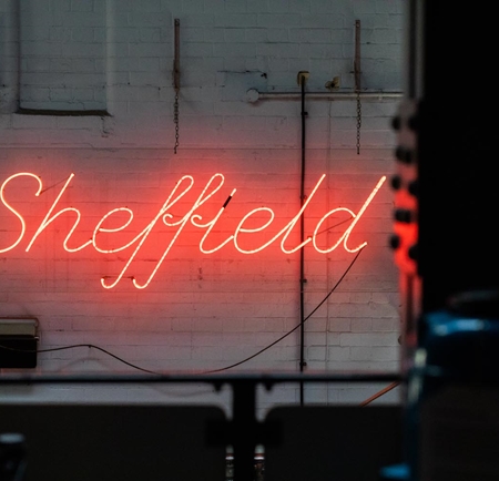 A red neon sign in a window that reads 'Sheffield'.