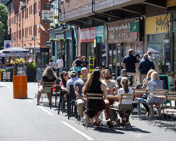 People sat at tables, outside restaurants, eating in the sunshine.