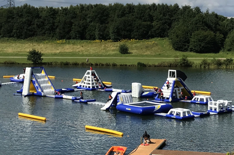 A variety of inflatable obstacles are floating on a lake.