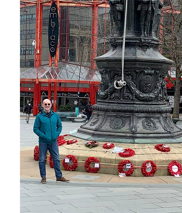 A man stands next to the War Memorial in Barkers Pool, Sheffield.