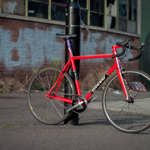 A classic racing bike leaning against a lamppost.