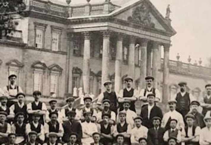 An old black and white image of a group of men posing with Wentworth Woodhouse in the background.