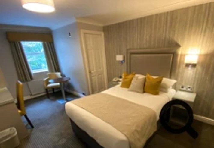 Bedroom at Cubley Hall with double bed, bedside tables, and lamp.