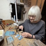 Person working at a jeweller’s bench using hand tools to craft a piece of jewellery.