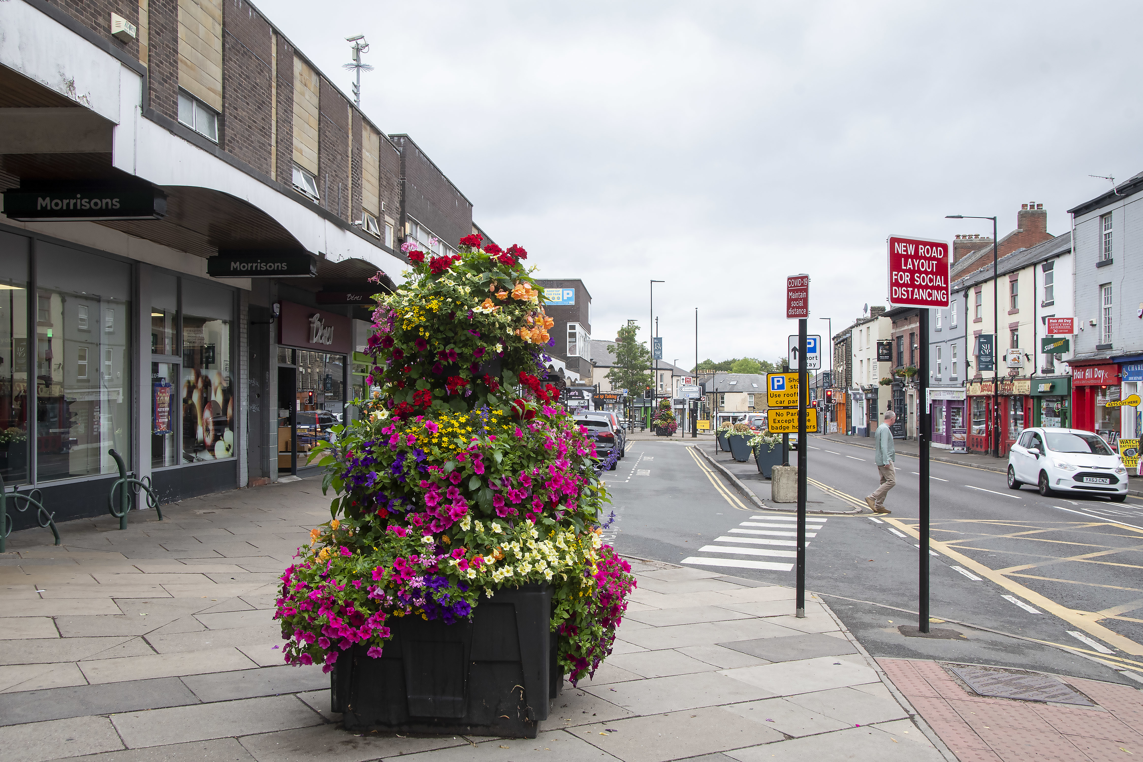 A large display of flowers in a huge planter on the pavement.