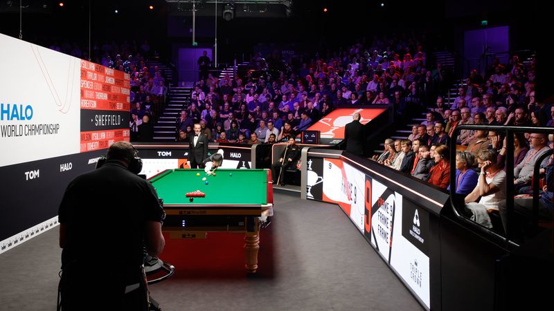 A snooker table is set up and a crowd waits for the frame to start.