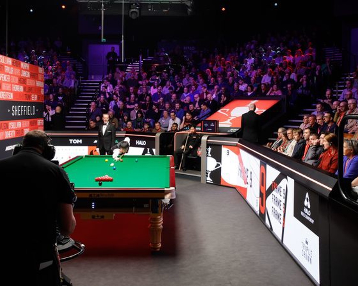 A snooker table is set up and a crowd waits for the frame to start.