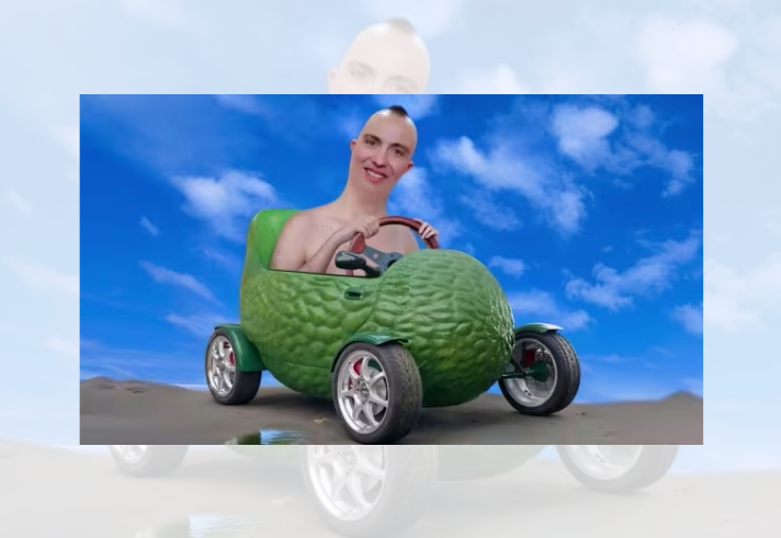 A surreal digital image showing a person seated in a small car shaped like a giant green avocado. The avocado vehicle has a textured exterior, shiny silver wheels and an open-top design with a steering wheel visible inside. The vehicle is parked on a sandy surface beneath a bright blue sky with scattered white clouds. The scene has a playful, computer-generated appearance.