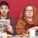 Ian Smith and Amy Gledhill are sat at a table covered in newspapers.