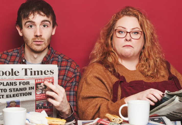 Ian Smith and Amy Gledhill are sat at a table covered in newspapers.
