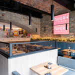  The interior of Tavern on The Quays, with bare stone walls and rows of tables and chairs.