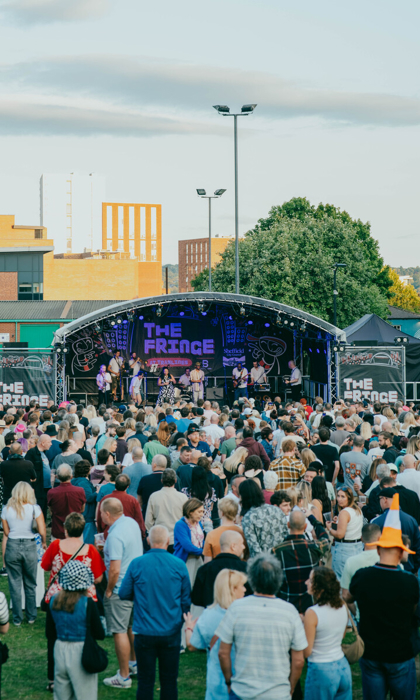 Outdoor stage at The Fringe at Tramlines with a live band performing to a packed crowd in front of Devonshire Green.