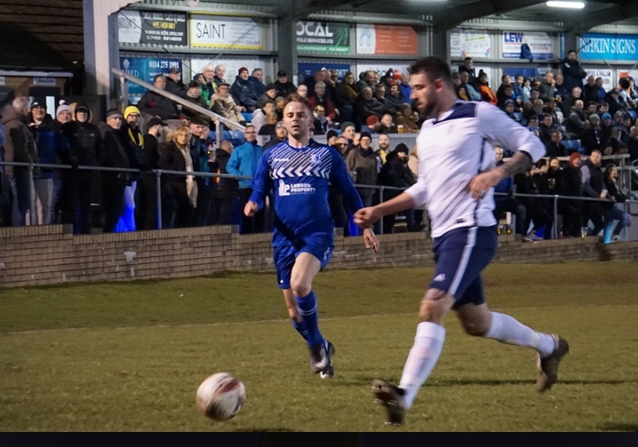 Men playing football in front of a crowd.