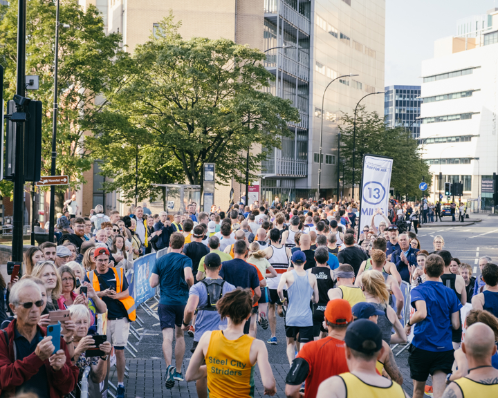 Group of people taking part in Sheffield Half Marathon, running along Arundel Gate.