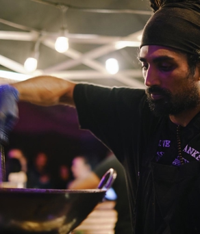A young male chef cooking using a wok in an open kitchen-restaurant. 
