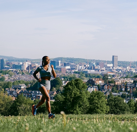 Runner in Meersbrook Park with cityscape view in the background