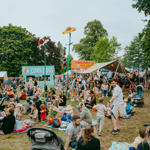 Families sit out on picnic blankets eating as other people queue for food from street food stalls at Tramlines festival 
