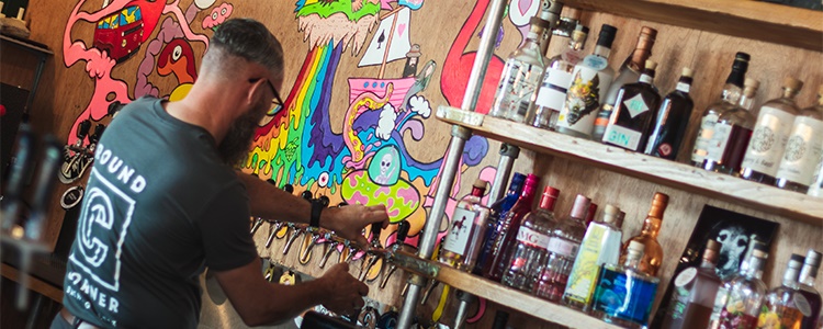 A man works behind a well stocked bar.