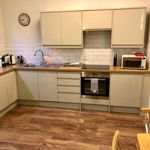 Small but functional kitchen at Homely Apartments – Figtree featuring stove, sink, and storage