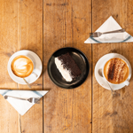 Two coffees on a rustic wooden table.