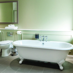 Classic white roll-top bath with chrome fittings in a stylish hotel bathroom.