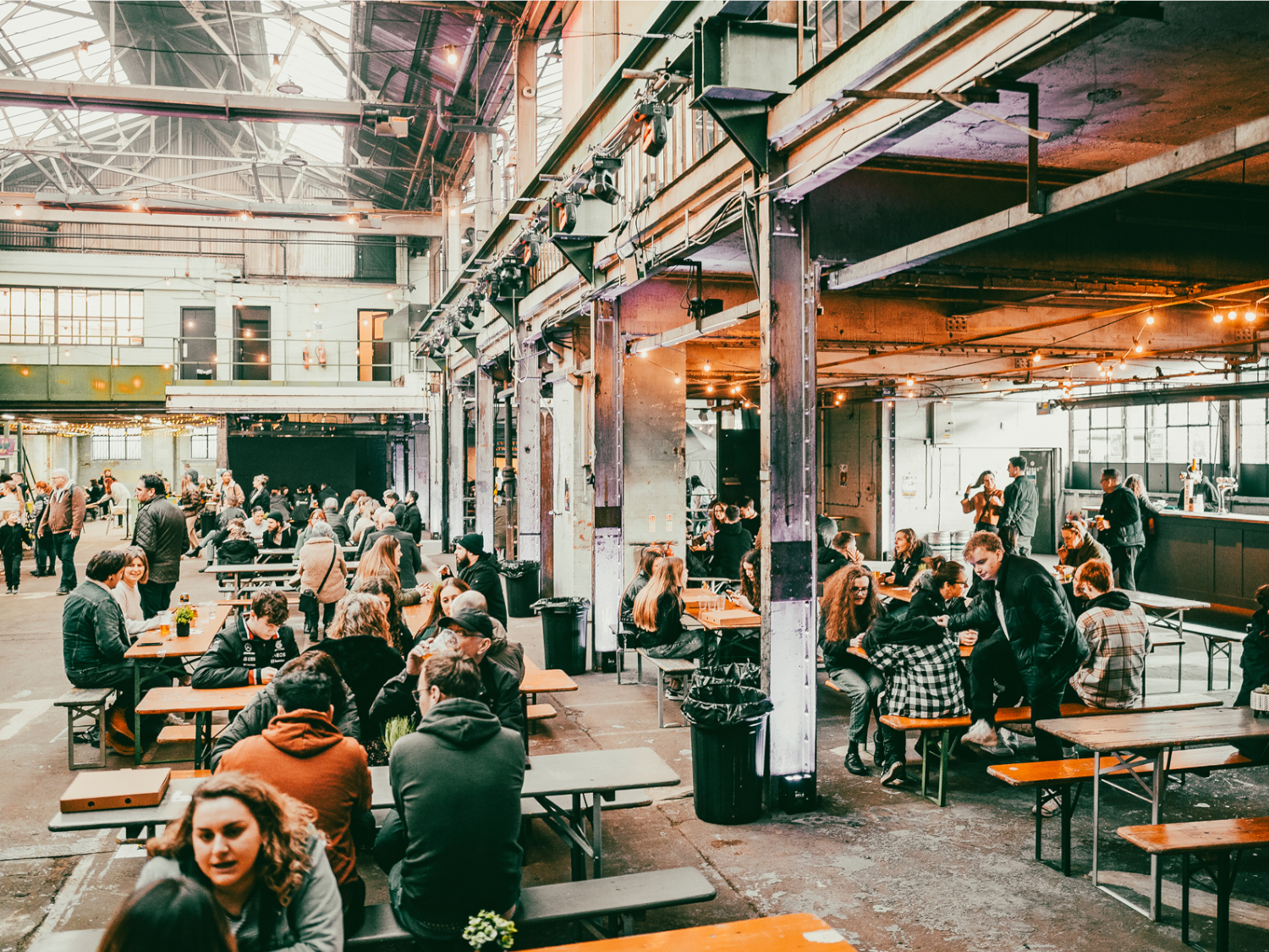 Rows of tables with benches, with people dining, at The Steamworks.