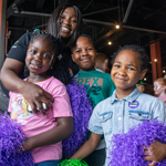 Three children, all holding pompoms, at a Boomchikkaboom family rave.