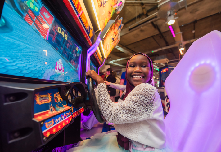 A child having fun playing an arcade style video game.