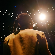 A woman delivers a presentation to a crowd in a darkened room.