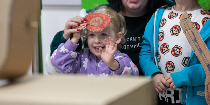 Two children and an adult looking at a video game.