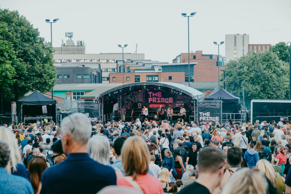 Outdoor stage at The Fringe at Tramlines with a live band performing to a packed crowd in front of Devonshire Green.