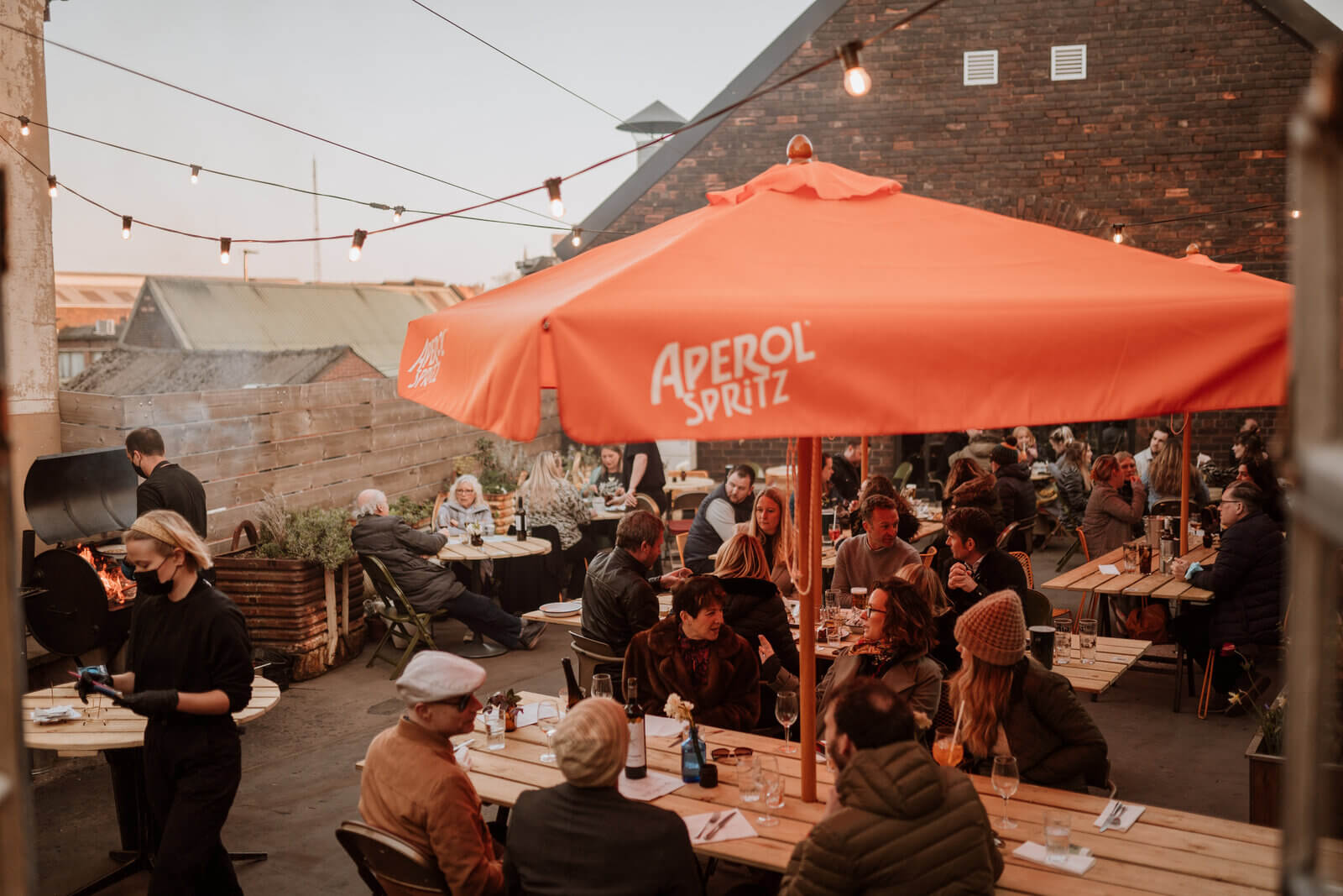 People eating outside at The Mowbray sat under large orange parasols.