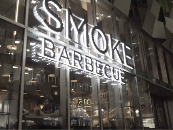 The Smoke BBQ sign lit up at night.