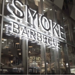 The Smoke BBQ sign lit up at night.