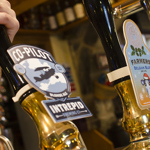 A hand pulling on a beer pump on a bar.