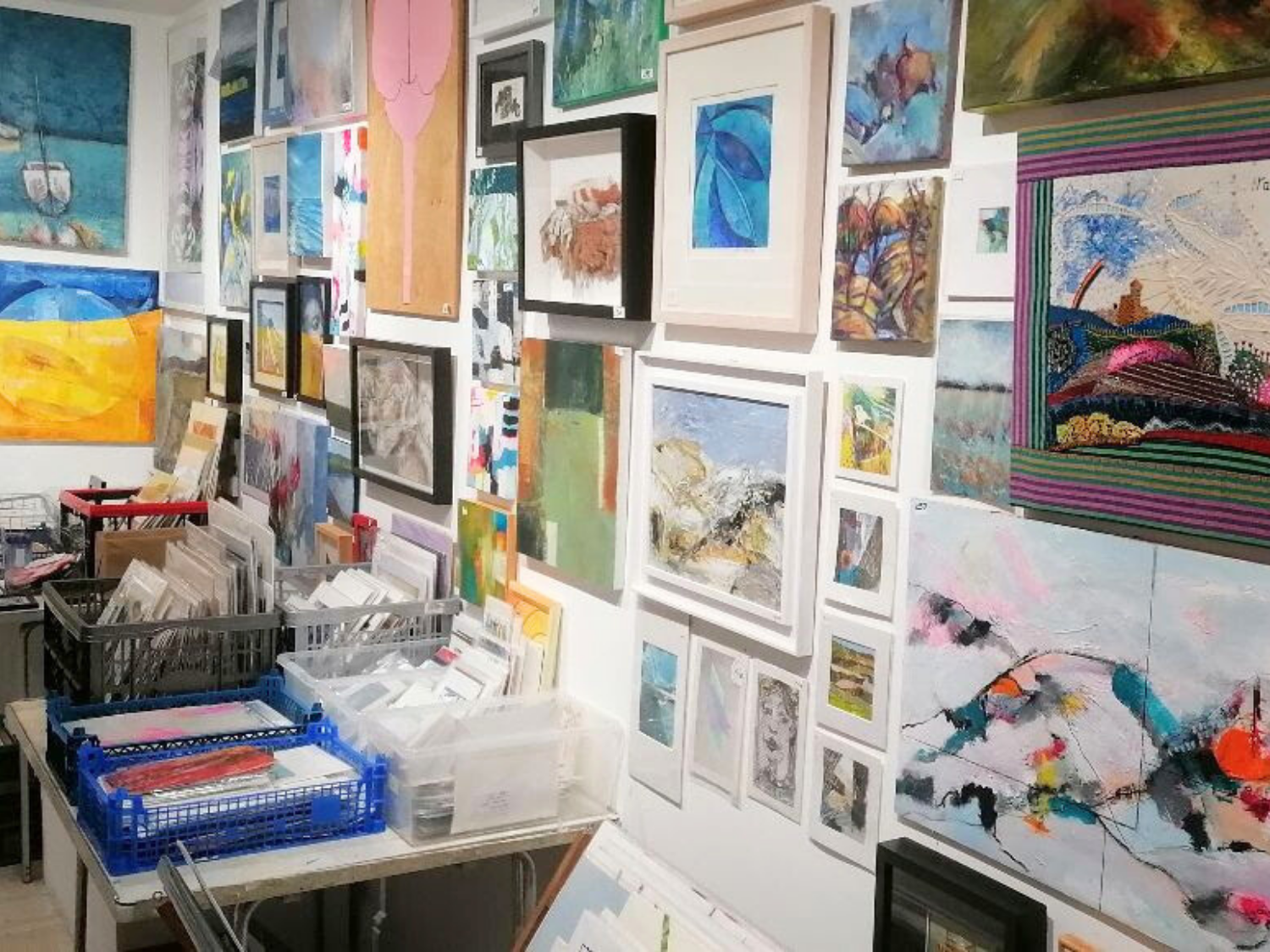 A gallery wall covered in paintings and artworks of all sizes.