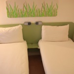 Bright bedroom featuring two neatly made single beds side by side.