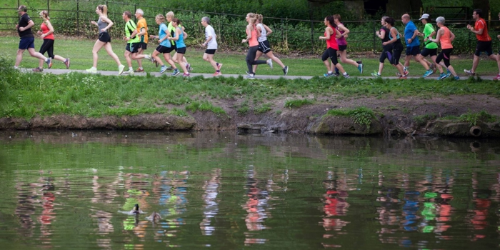 Group of runners participating in a park run alongside a lake.