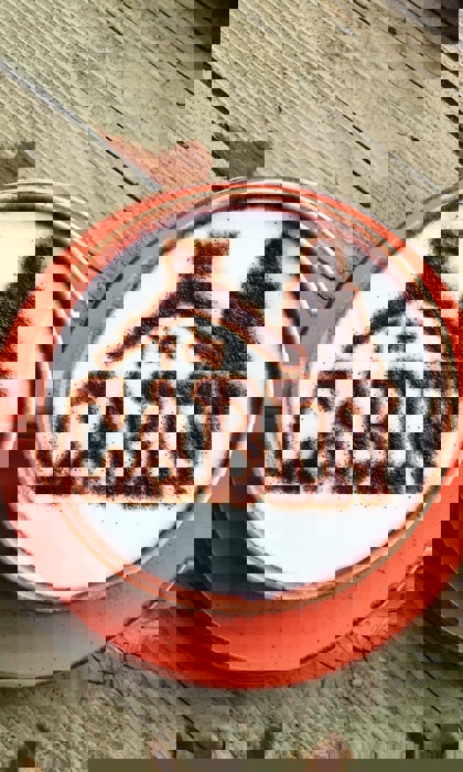 A cappuccino with The Cabin logo dusted onto the froth in chocolate powder.