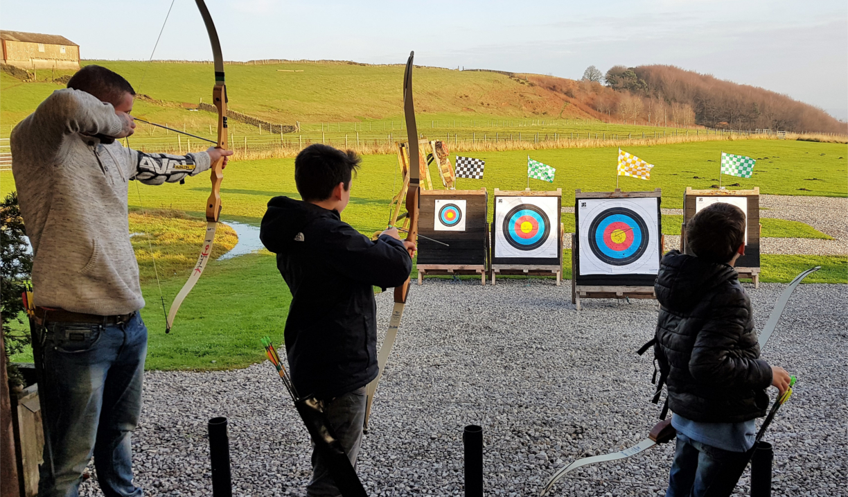 Three people doing archery at the Ringinglow Archery Target Sports Centre.