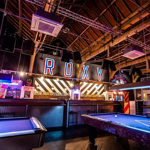 Interior of the Roxy Ball Room with bright neon lights, a bar and gaming tables.