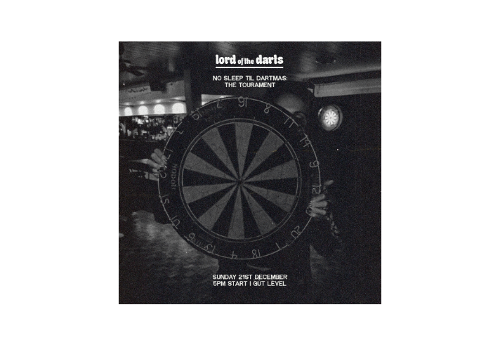 Black-and-white promotional image for a darts event. A person holds a large dartboard in the centre, partially obscuring their face. The background shows a dimly lit bar with another dartboard on the wall. White text at the top reads “lord of the darts” followed by “NO SLEEP TIL DARTMAS: THE TOURNAMENT.” At the bottom, text states “SUNDAY 21ST DECEMBER, 5PM START | GUT LEVEL.” The overall design has a gritty, high-contrast aesthetic.