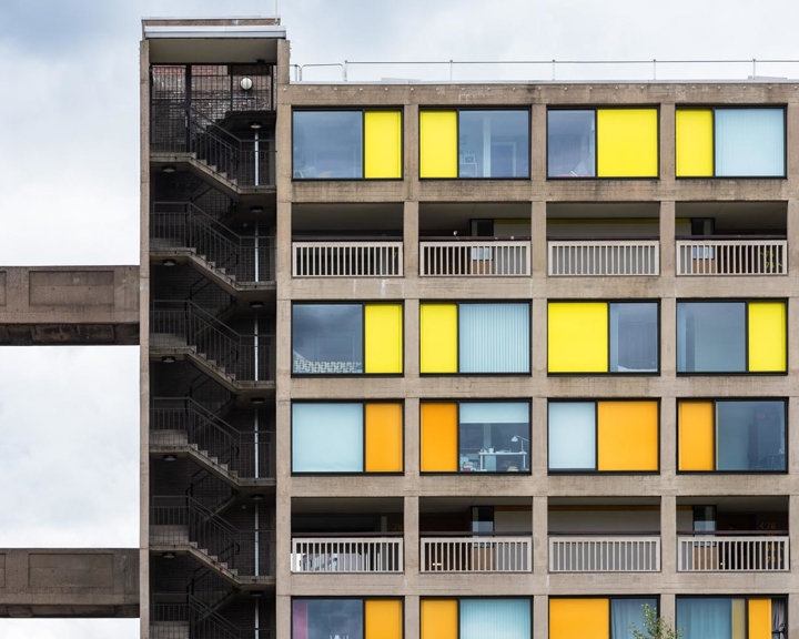 A tower block with rows of alternating windows and bright yellow or orange panels. At one end is a tower with stairs running all through it.