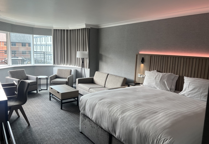 Modern double bedroom with seating area and ambient mood lighting.