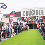 Crowds line a green carpet outside the Crucible Theatre for a Sheffield Loves Snooker event, with colourful flags and the theatre’s bold façade in the background.