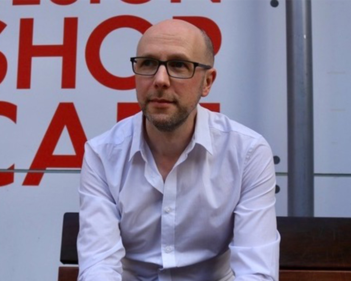 A photo of a man in a white shirt looking off to the side.