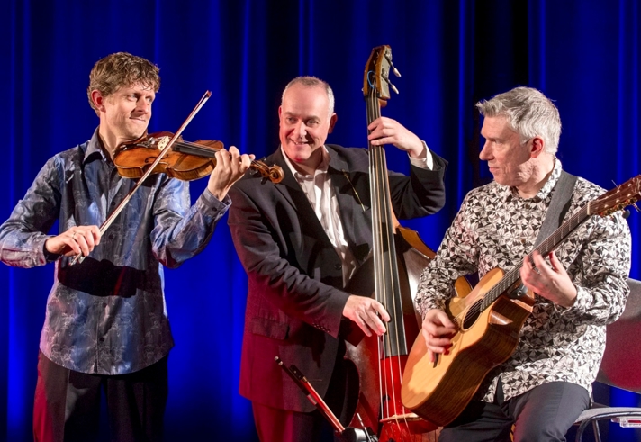 A trio playing guitar, violin and double bass.