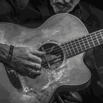 A black and white image of Dylan Fowler playing a classical guitr.