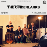 Promotional poster for a Sidney & Matilda gig. Large text reads “The Cinderlarks” with support from “The Zebedees.” Date: 13/11/26. Venue branding and website appear at the top. The main image shows four band members seated in a rehearsal or studio space surrounded by instruments, including acoustic and electric guitars, a bass guitar, drums and amplifiers. Warm indoor lighting and neutral tones create a relaxed group portrait.