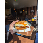 A delicious sausage and egg sandwich being held aloft in the Copper Pot Café.